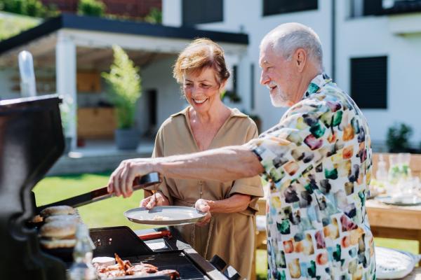 Ein älteres Ehepaar grillt Essen auf dem Grill