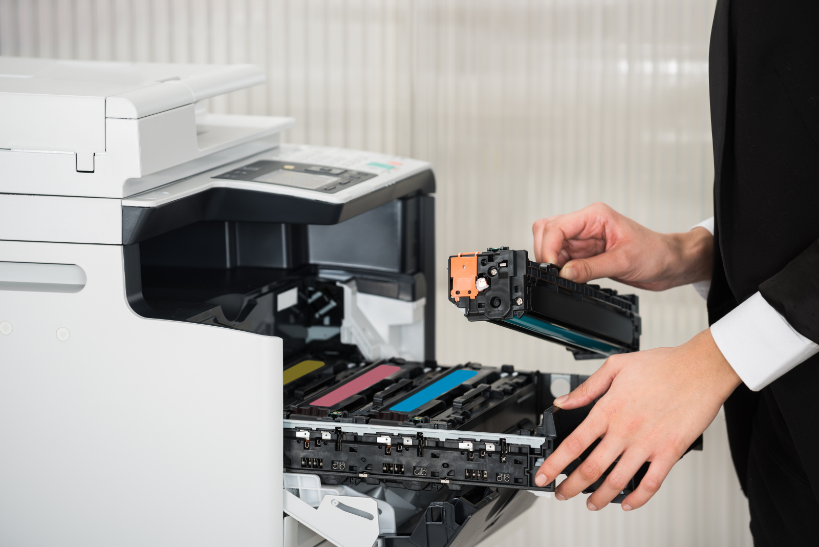 Eine Frau im Büro, die den Toner eines großen Laserdruckers austauscht.